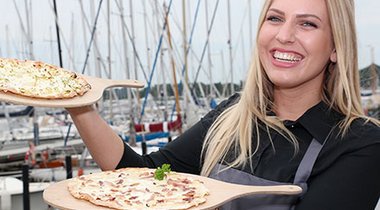 Nahaufnahme von Person mit Speisen aus den Gastrobetrieben des Schleswiger Stadthafens.